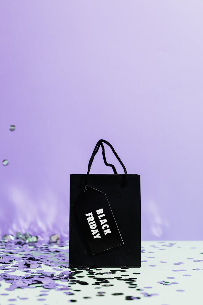 A stylish black shopping bag with a 'Black Friday' tag against a decorative purple backdrop.