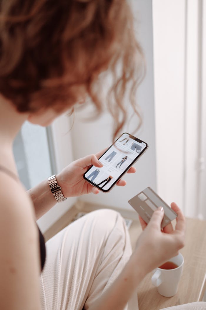 A woman using a smartphone for online shopping, holding a credit card.