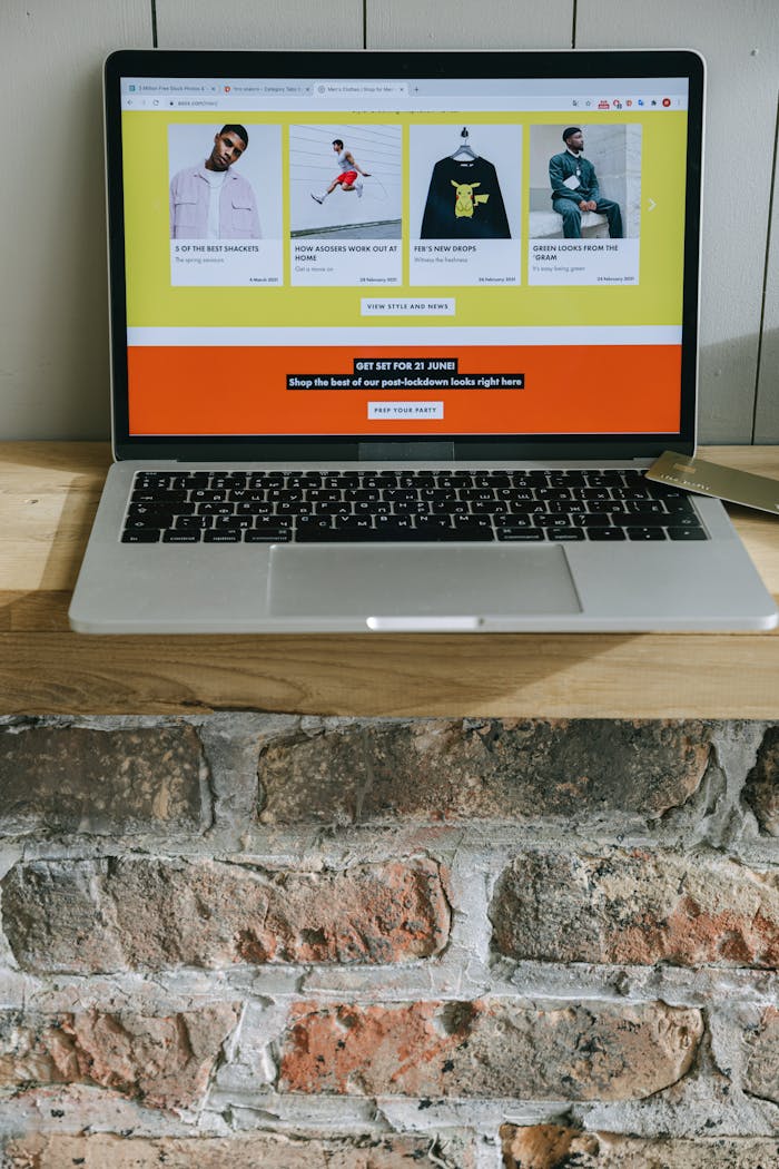 A laptop on a wooden shelf showing a colorful online shopping webpage.